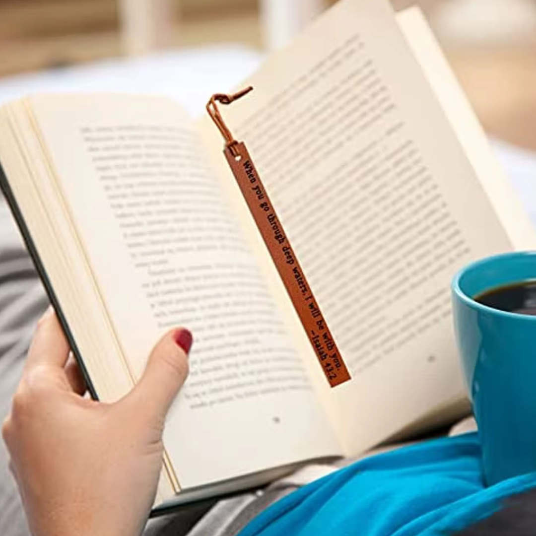 Open book with a brown bookmark on the page and a blue coffee cup nearby.